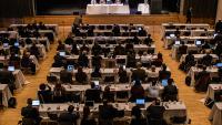 A group of people meet in a large conference space.
